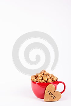 Delicious caramel popcorn in red mug and wooden heart. Romantic concept.