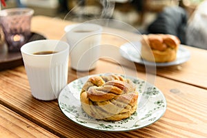 Delicious cardamom buns and coffee on table in cafe