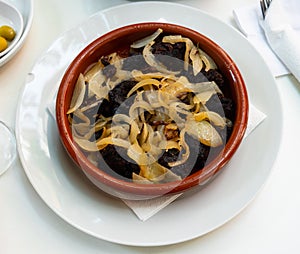 Delicious Catalan blood sausages with grilled onion served on plate. Morcilla con cebolla photo
