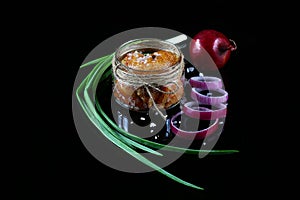 Delicious caviar, roe close up, pike caviar in a transparent jar, purple onion cut into rings on a black background, top view, set