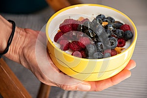 Delicious ceramic yellow bowl with fresh berries (raspberries and blackberries) and cereals
