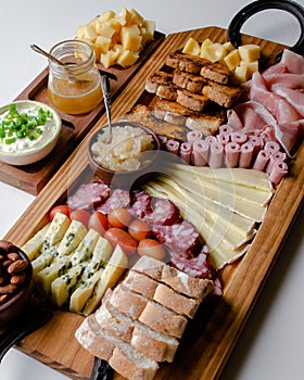 Delicious Charcuterie Board with snacks cheese, toast, ham, blue cheese, almonds, caramelized onions, green onion, honey, toast.