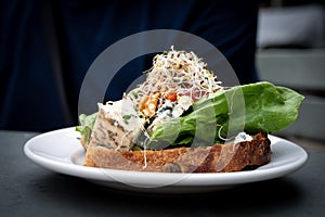 A delicious cheese sandwhich topped with walnuts, marmelade, and vegetables