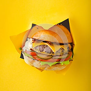 Delicious cheeseburger coming out of yellow colored background