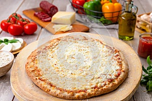 Delicious cheesy whole baked pizza pie with extra cheese, with ingredients on table