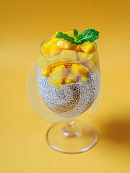Delicious chia pudding parfait with fresh mango and mint on vibrant orange background