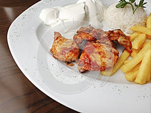 Delicious chicken shish kebab served with rice, fries and yogurt in a restaurant