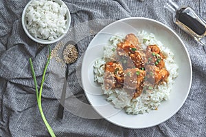 Delicious chicken with sweet and sour orange sauce accompanied by jasmine rice Chinese-style recipe, top view.