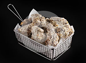 Delicious chicken wings covered in cheese in a frying basket isolated on a black background