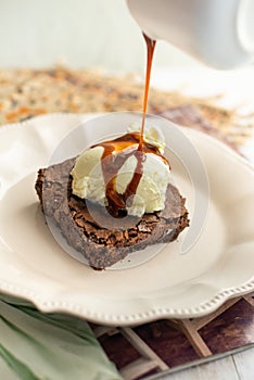 Delicious chocolate brownie with ice cream and caramel syrup falling