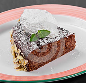 Delicious chocolate cake with almond and vanilla ice cream on plate on dark wooden background, sweet food