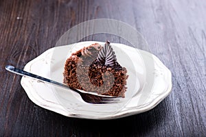 Delicious chocolate cake on plate on dark wooden table