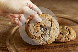 Delicious Chocolate Chip Cookies on wooden plate on wooden table. Fresh baked chocolate chip cookies on rustic wooden table.