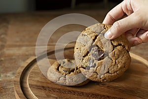 Delicious Chocolate Chip Cookies on wooden plate on wooden table. Fresh baked chocolate chip cookies on rustic wooden table.