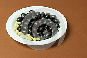 Delicious Chocolate Covered Peanuts Arranged on White Plate Against Brown Background