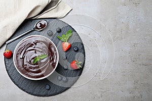 Delicious chocolate cream with berries and mint on grey table, top view. Space for text