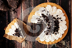 Chocolate cream pie, top view scene with slice removed on dark wood photo