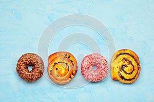 Delicious chocolate donuts and buns with poppy seeds and raisins on a light turquoise surface photo