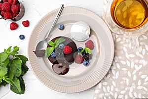 Delicious chocolate fondant served with fresh berries and ice cream on white table, flat lay