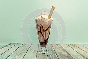 Delicious chocolate milkshake with syrup, whipped cream and a cookie straw