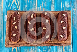 Delicious chocolate and peanut eclairs on a blue wooden table