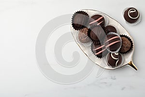 Delicious chocolate truffles on white marble table, flat lay. Space for text