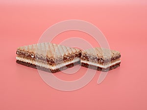 Delicious chocolate wafers with hazelnuts on a pink background.