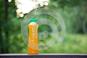 Delicious citrus juice in a plastic bottle on the background of summer nature