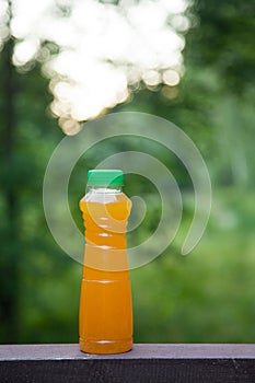 Delicious citrus juice in a plastic bottle on the background of summer nature