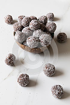 Delicious Coconut-Chocolate balls covered with grated coconut served in a coconut plate against white background