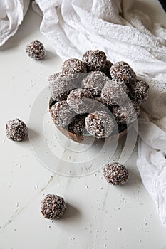 Delicious Coconut-Chocolate balls covered with grated coconut served in a coconut plate against white background