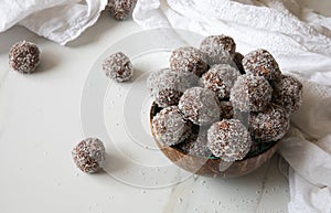 Delicious Coconut-Chocolate balls covered with grated coconut served in a coconut plate against white background