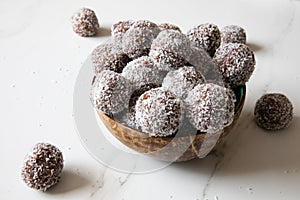Delicious Coconut-Chocolate balls covered with grated coconut served in a coconut plate against white background