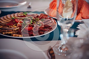 Delicious cold appetizers on plate, close-up. Thin slicing of meat delicacies at festive banquet. Pastrami and boiled pork,