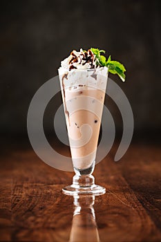 Delicious cold chocolate ice cream milkshake with mint leaves in a long glass