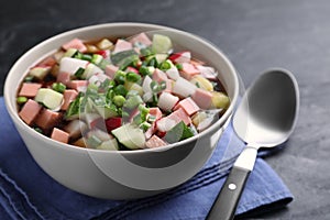 Delicious cold okroshka with kvass served on black table, closeup. Traditional Russian summer soup