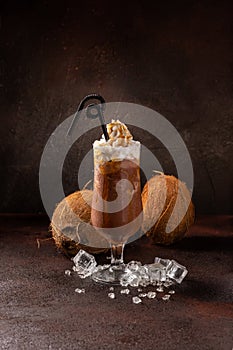 Delicious cold refreshing ice coffee in cocktail glass with coconut