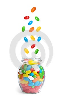 Delicious color jelly beans falling into jar on background