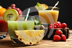 Delicious colorful juice in glass and fresh ingredients on wooden table, closeup