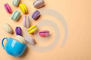 Delicious colorful macarons and cup on beige background, flat lay. Space for text