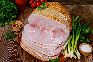 Delicious cooked ham on a wooden board with green onion and radish