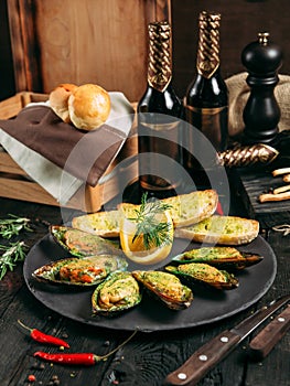 Delicious cooked mussels with sauce, lemon and garlic bread and butter