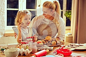 Delicious cookies and pastry. Happy young woman, mother cooking sweet, baking with her little daughter at home in winter