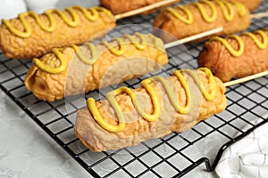 Delicious corn dogs with mustard on grey table, closeup