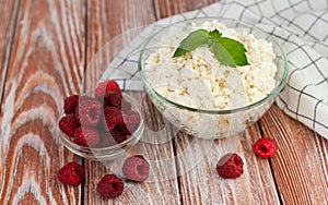Delicious cottage cheese and ripe raspberries on the wooden table. Healthy breakfast. Close-up