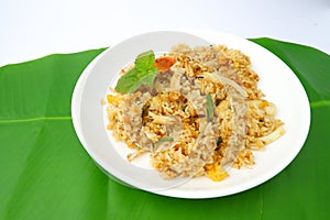 Delicious crab fried rice on a white plate on a green leaf background.