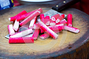 Delicious crab sticks prepared for eating. Crab sticks with lettuce and dill on brown wooden cutting board.