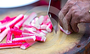 Delicious crab sticks prepared for eating. Crab sticks with lettuce and dill on brown wooden cutting board. Crab sticks on cuttin