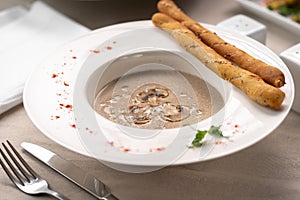 Delicious cream soup puree with mushrooms serving with breadsticks