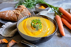 Delicious creamy carrot soup with turmeric powder and baguette